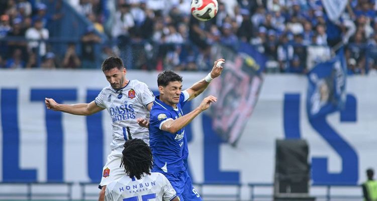 persib-bandung-juara-super-league.webp Striker Persib Bandung duel udara berebut bola dengan pemain bertahan lawan demi mengunci gelar juara Super League.