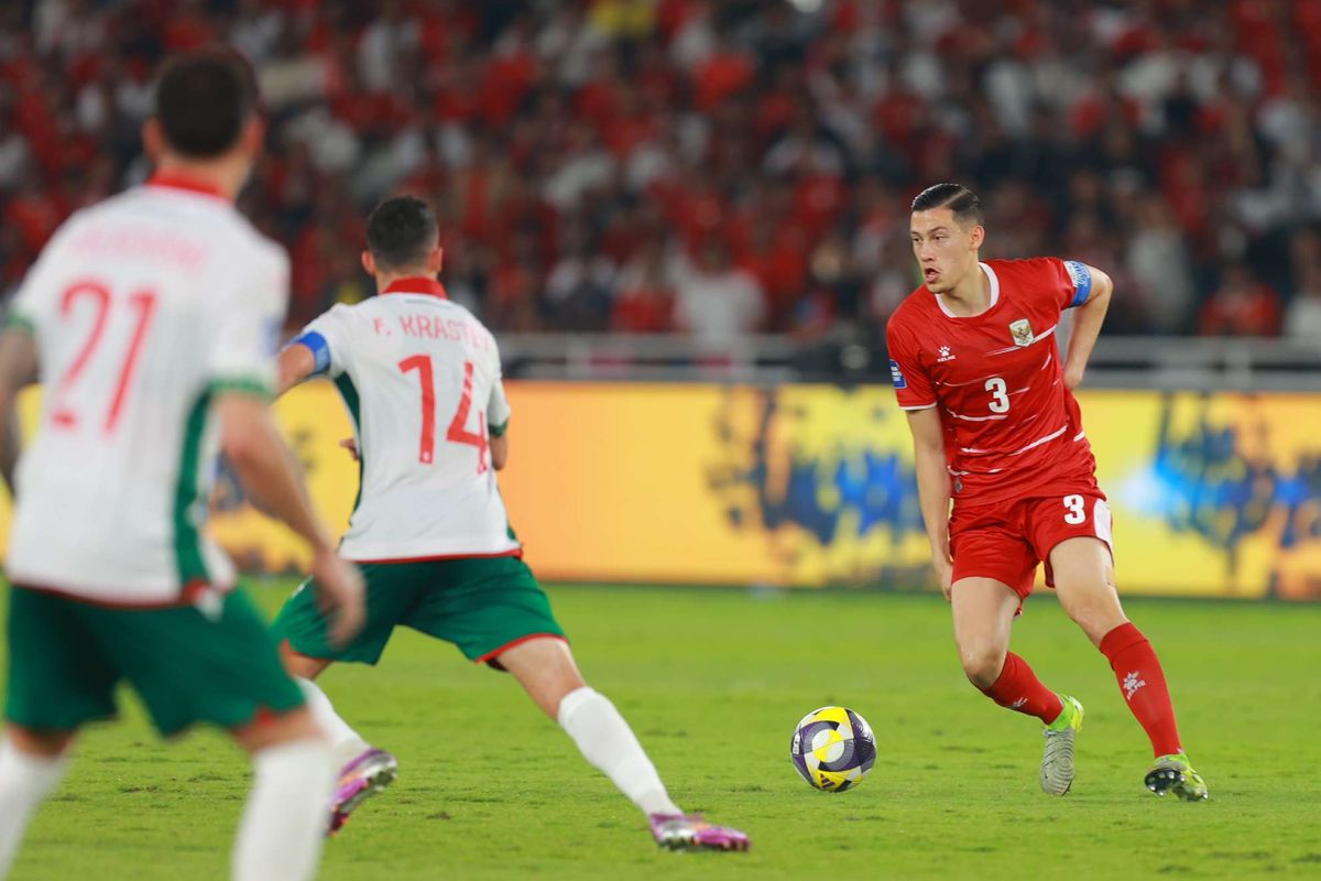 Jay Idzes saat mengontrol bola dalam pertandingan Timnas Indonesia menggunakan jersey merah bernomor punggung 3.