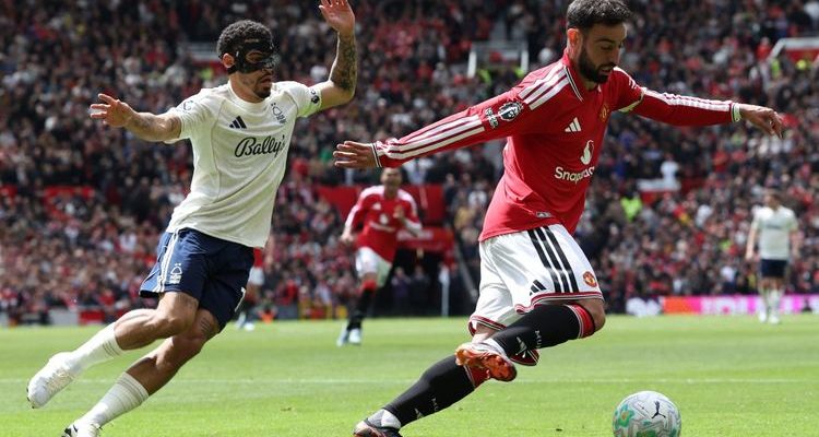 Kapten Manchester United Bruno Fernandes sedang menggiring bola melewati kawalan pemain Nottingham Forest dalam pertandingan Liga Inggris di Old Trafford.