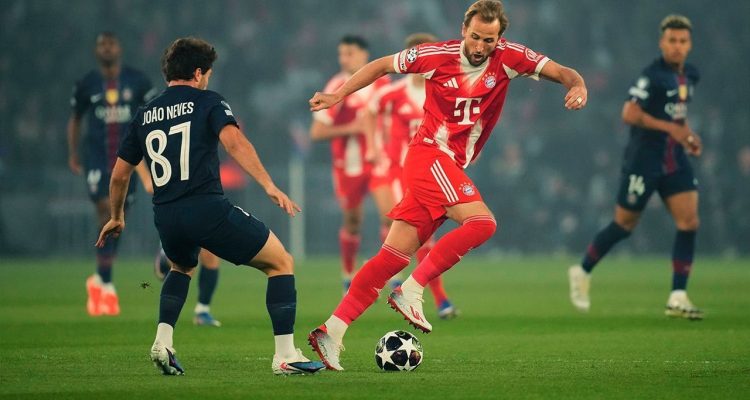 Harry Kane dari Bayern München sedang mendribel bola melewati pemain PSG João Neves dalam pertandingan Liga Champions di Allianz Arena.