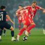 Harry Kane dari Bayern München sedang mendribel bola melewati pemain PSG João Neves dalam pertandingan Liga Champions di Allianz Arena.