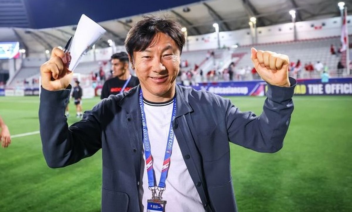 Pelatih Shin Tae-yong tersenyum ramah sambil mengepalkan tangan di area stadion sepak bola. Persija Jakarta