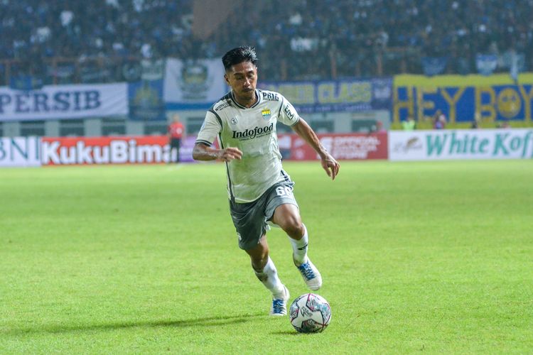 Daisuke Sato saat mengenakan jersey Persib Bandung tengah menggiring bola dengan lincah di lapangan hijau dalam pertandingan resmi.