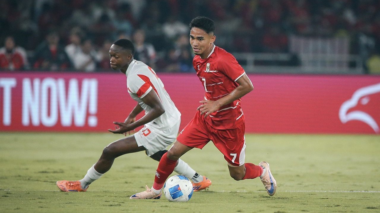 Pemain Timnas Indonesia dengan jersey merah sedang menggiring bola melewati pemain Mozambik dalam laga FIFA Matchday.
