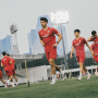 Para pemain Timnas Indonesia mengenakan jersey latihan merah sedang berlari di lapangan sepak bola luar ruangan.