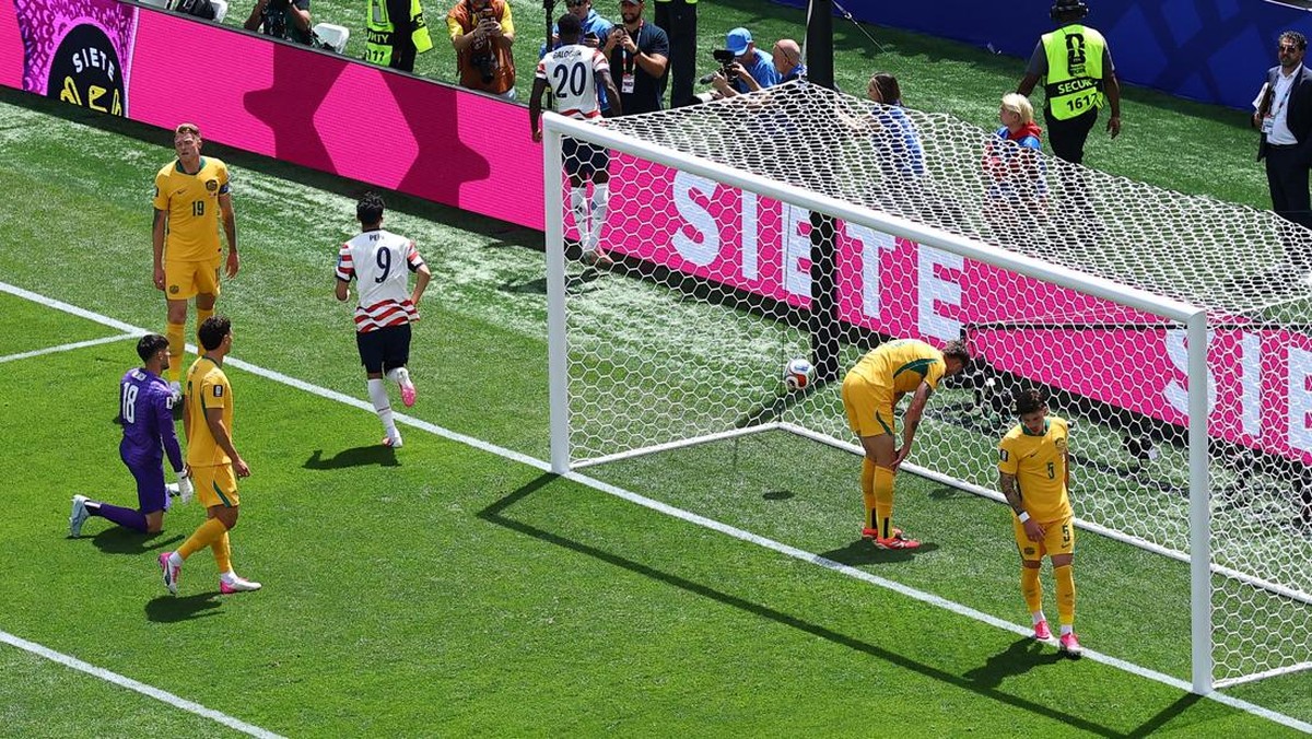 Pemain timnas Amerika Serikat nomor punggung 9 merayakan gol ke gawang Australia yang dijaga kiper berbaju ungu dalam pertandingan Piala Dunia.