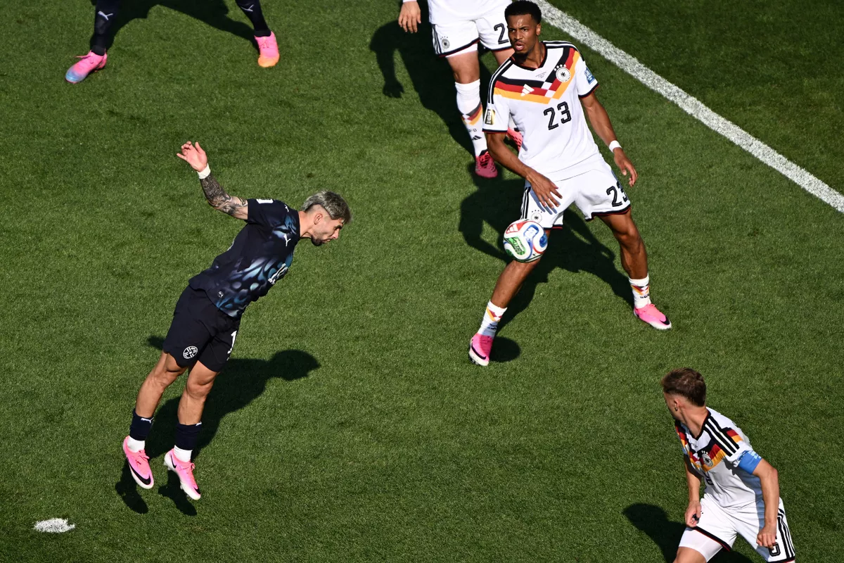 Pemain timnas Jerman menghadang pergerakan pemain Paraguay yang melompat menyundul bola dalam laga Piala Dunia.