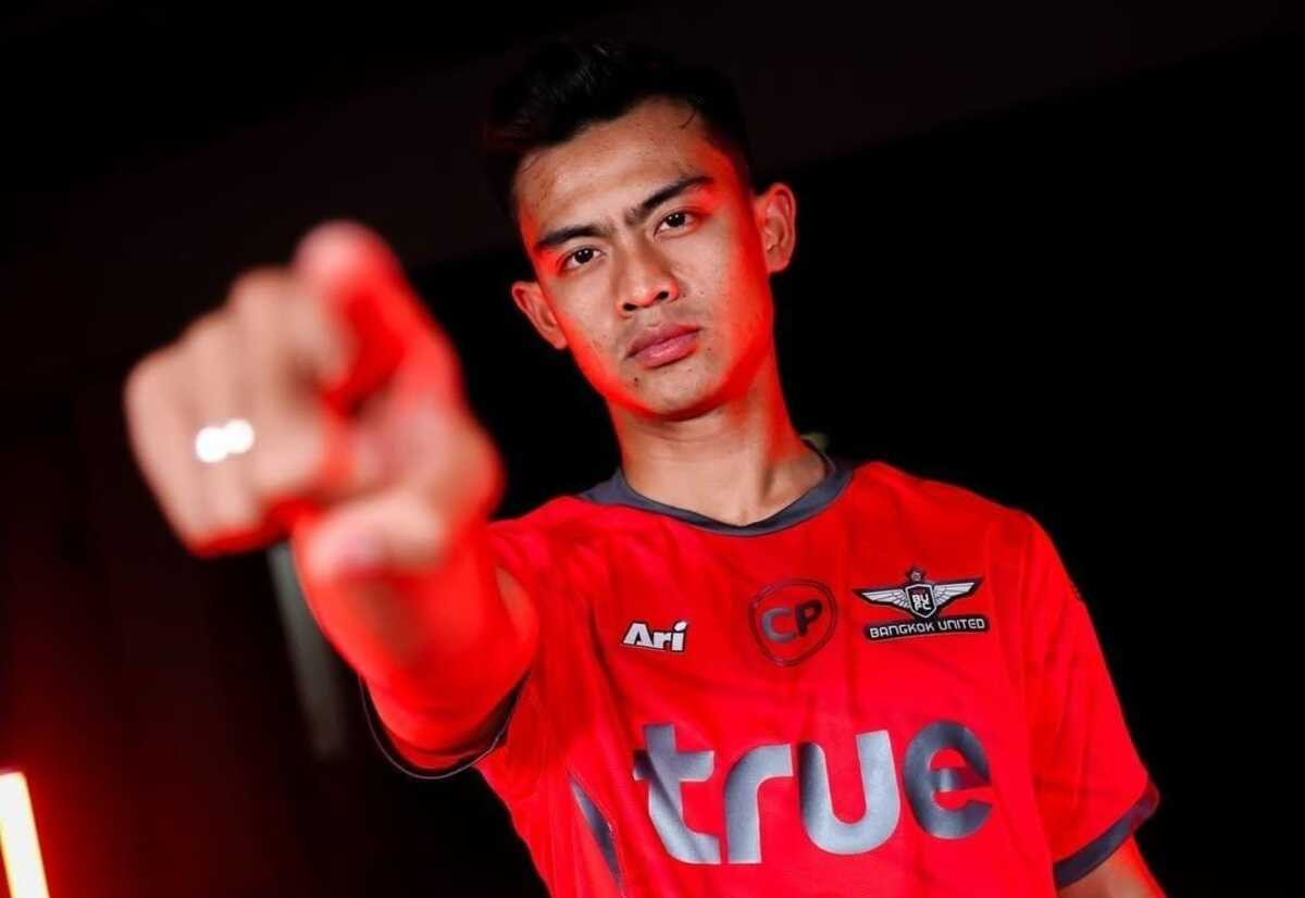 Pemain sepak bola Timnas Indonesia, Pratama Arhan, berpose menunjuk ke arah kamera sambil mengenakan jersey merah resmi Bangkok United FC.