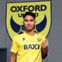 Marselino Ferdinan mengenakan jersi kuning dengan latar belakang logo klub Oxford United