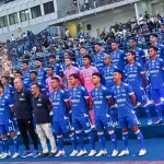 Skuat lengkap Persib Bandung berfoto bersama mengenakan jersey biru di tepi lapangan sebelum pertandingan dimulai.