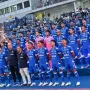 Skuat lengkap Persib Bandung berfoto bersama mengenakan jersey biru di tepi lapangan sebelum pertandingan dimulai.