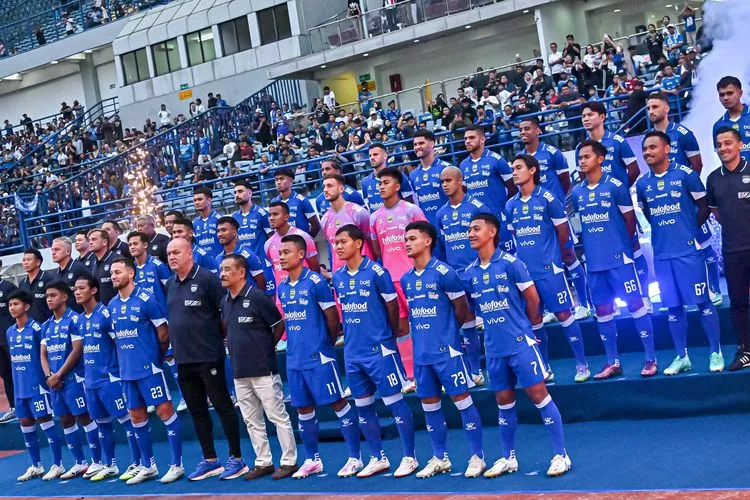 Skuat lengkap Persib Bandung berfoto bersama mengenakan jersey biru di tepi lapangan sebelum pertandingan dimulai.