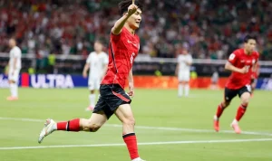 Gelandang Korea Selatan Hwang In-beom berlari merayakan gol dengan menunjuk ke atas di lapangan sepak bola.