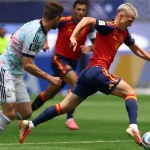 Gelandang timnas Spanyol, Mikel Merino, sedang menggiring bola dengan cepat melewati kawalan ketat bek Belgia dalam duel sengit babak perempat final.