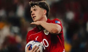 Striker Ole Romeny mengenakan jersey merah Timnas Indonesia berlambang Garuda sambil memegang bola di lapangan.