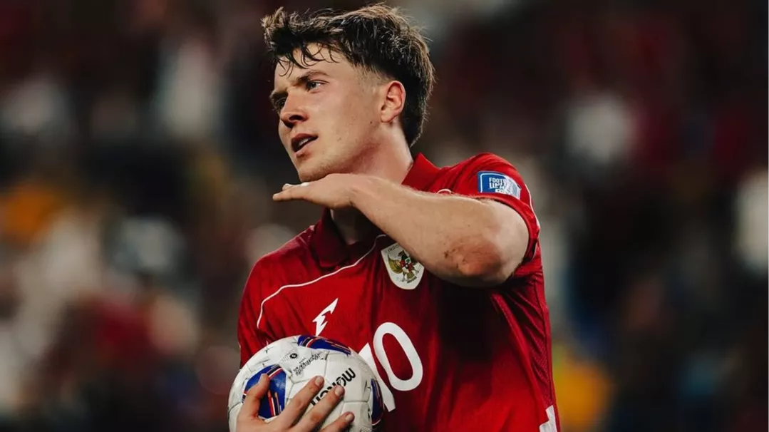 Striker Ole Romeny mengenakan jersey merah Timnas Indonesia berlambang Garuda sambil memegang bola di lapangan.