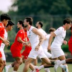 Skuad Timnas Indonesia mengenakan jersey latihan merah dan putih sedang berlari memanaskan fisik di lapangan.