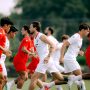 Skuad Timnas Indonesia mengenakan jersey latihan merah dan putih sedang berlari memanaskan fisik di lapangan.