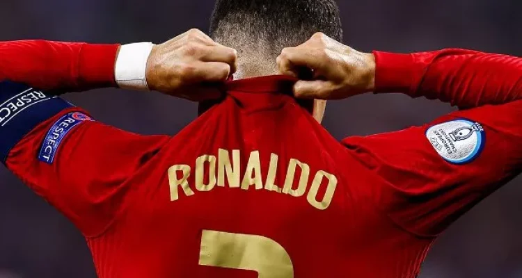 cristiano-ronaldo-kecewa-portugal-disingkirkan-spanyol.webp Tampak belakang Cristiano Ronaldo menarik bagian belakang jersei Portugal nomor 7 miliknya dengan ekspresi kecewa usai kalah dari Spanyol.