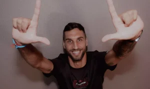 denis-kolinger-bek-baru-persija-jakarta.webp Denis Kolinger, bek asing baru Persija Jakarta asal Jerman-Kroasia, tersenyum ke arah kamera sambil membentuk simbol "L" (The Jakmania) dengan kedua tangannya.