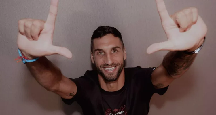 denis-kolinger-bek-baru-persija-jakarta.webp Denis Kolinger, bek asing baru Persija Jakarta asal Jerman-Kroasia, tersenyum ke arah kamera sambil membentuk simbol "L" (The Jakmania) dengan kedua tangannya.