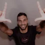 Denis Kolinger, bek asing baru Persija Jakarta asal Jerman-Kroasia, tersenyum ke arah kamera sambil membentuk simbol "L" (The Jakmania) dengan kedua tangannya.