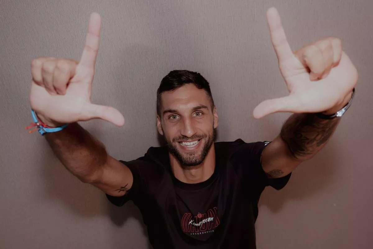 Denis Kolinger, bek asing baru Persija Jakarta asal Jerman-Kroasia, tersenyum ke arah kamera sambil membentuk simbol "L" (The Jakmania) dengan kedua tangannya.