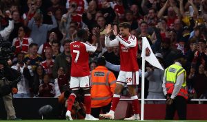 Pemain Arsenal Bukayo Saka dan Kai Havertz melakukan selebrasi high five di sudut lapangan di hadapan para pendukung.