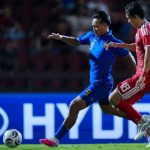 Striker Timnas Thailand, Teerasil Dangda (No. 9), berusaha melewati hadangan bek Singapura dalam pertandingan semifinal leg kedua Piala AFF 2026. Meski kalah tipis, Thailand berhasil mengunci tiket ke final berkat keunggulan agregat gol.