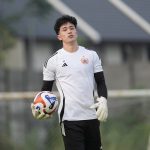Cyrus Margono mengenakan sarung tangan dan memegang bola dalam sesi latihan.