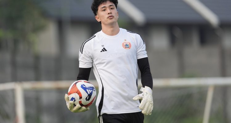 Cyrus Margono mengenakan sarung tangan dan memegang bola dalam sesi latihan.