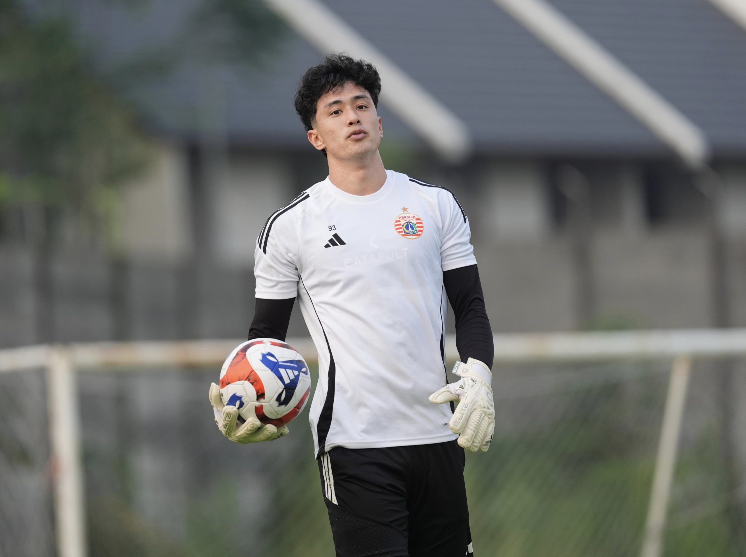 Cyrus Margono mengenakan sarung tangan dan memegang bola dalam sesi latihan.