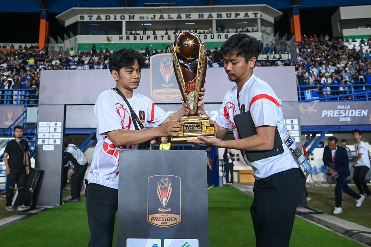 Petugas membawa dan meletakkan trofi resmi Piala Presiden di Stadion Si Jalak Harupat menjelang laga Semifinal Piala Presiden 2026.