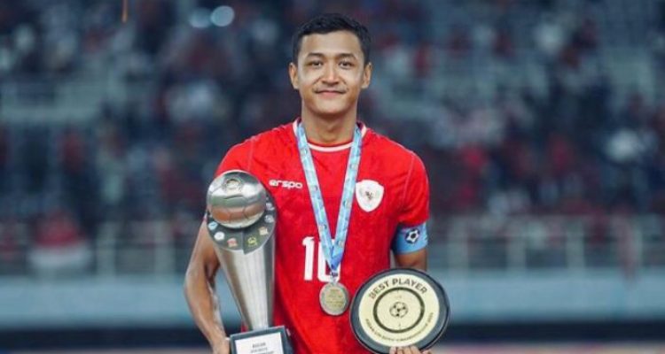 pemain-timnas-indonesia-eriko-sulastiano-melempem-lawan-singapura.webp Pemain Timnas Indonesia, Eriko Sulastiano, memegang trofi dan medali di lapangan stadion.