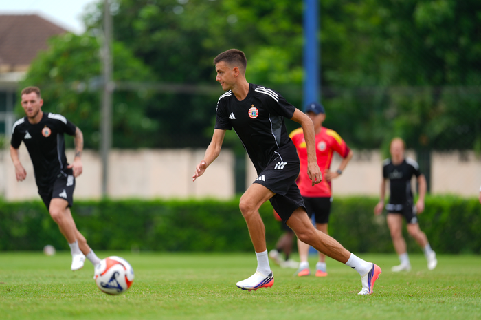 Alexander Jeremejeff mengenakan jersey latihan hitam Persija Jakarta saat mengontrol bola di lapangan.