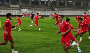Para pemain Timnas Indonesia mengenakan jersey merah sedang berlatih lari di lapangan stadion jelang laga ASEAN Cup 2026.