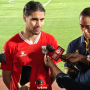 Kevin Diks mengenakan jersi merah Timnas Indonesia saat diwawancarai oleh para wartawan di pinggir lapangan.