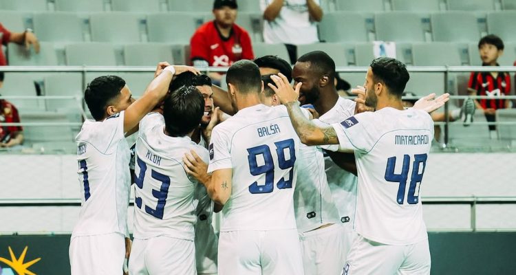 persib-bandung-selebrasi-menang-lawan-fc-seoul.webp Para pemain Persib Bandung berjersey putih saling berpelukan merayakan selebrasi kemenangan atas FC Seoul di lapangan.