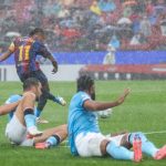 barcelona-vs-feyenoord-raphinha-tendangan.webp Raphinha pemain Barcelona melesakkan tendangan keras ke arah gawang Feyenoord di tengah hujan deras.