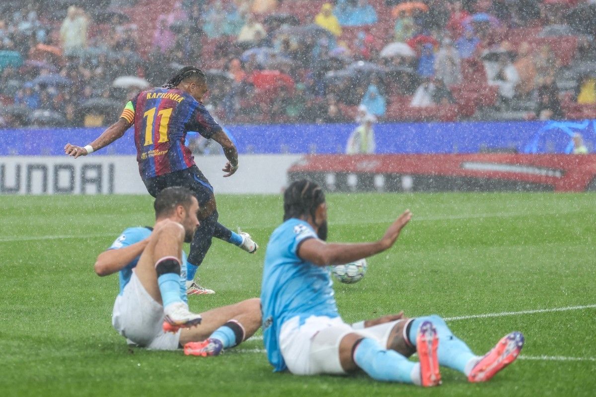 Raphinha pemain Barcelona melesakkan tendangan keras ke arah gawang Feyenoord di tengah hujan deras.