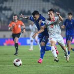 timnas-thailand-vs-vietnam-fifa-asean-cup.webp Pemain Timnas Thailand jersey biru berebut bola sengit dengan pemain Vietnam jersey putih di FIFA ASEAN Cup.