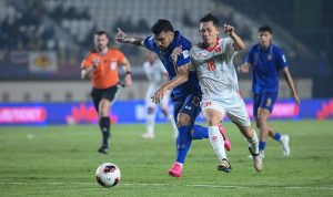 timnas-thailand-vs-vietnam-fifa-asean-cup.webp Pemain Timnas Thailand jersey biru berebut bola sengit dengan pemain Vietnam jersey putih di FIFA ASEAN Cup.