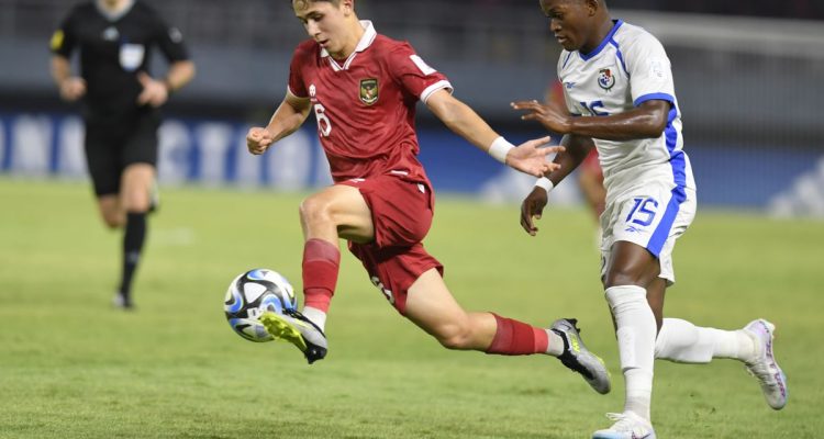 Amar Brkic mengontrol bola saat membela Timnas Indonesia U-17 menghadapi pemain lawan di lapangan hijau.