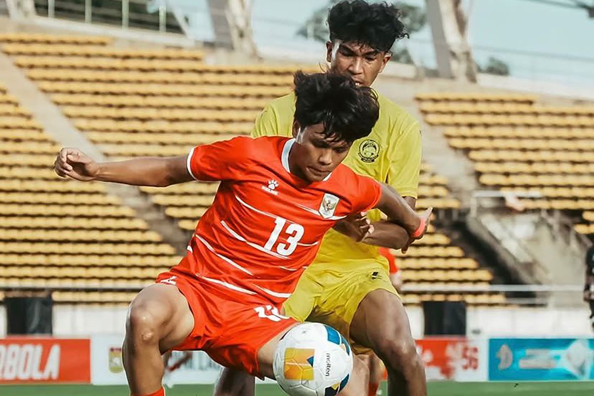 Pemain Timnas Indonesia U-20 dengan jersey merah nomor 13 berebut bola dengan pemain Malaysia .