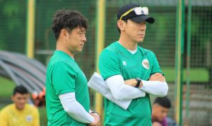 Pelatih Shin Tae-yong mengenakan topi hitam dan baju hijau sedang bersedekap mengamati sesi latihan Timnas.