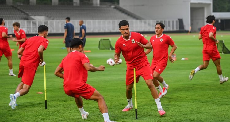 suasana-latihan-timnas-indonesia-persiapan-tanding.webp Skuad pemain menjalani sesi latihan Timnas Indonesia dengan seragam latihan merah di lapangan hijau.