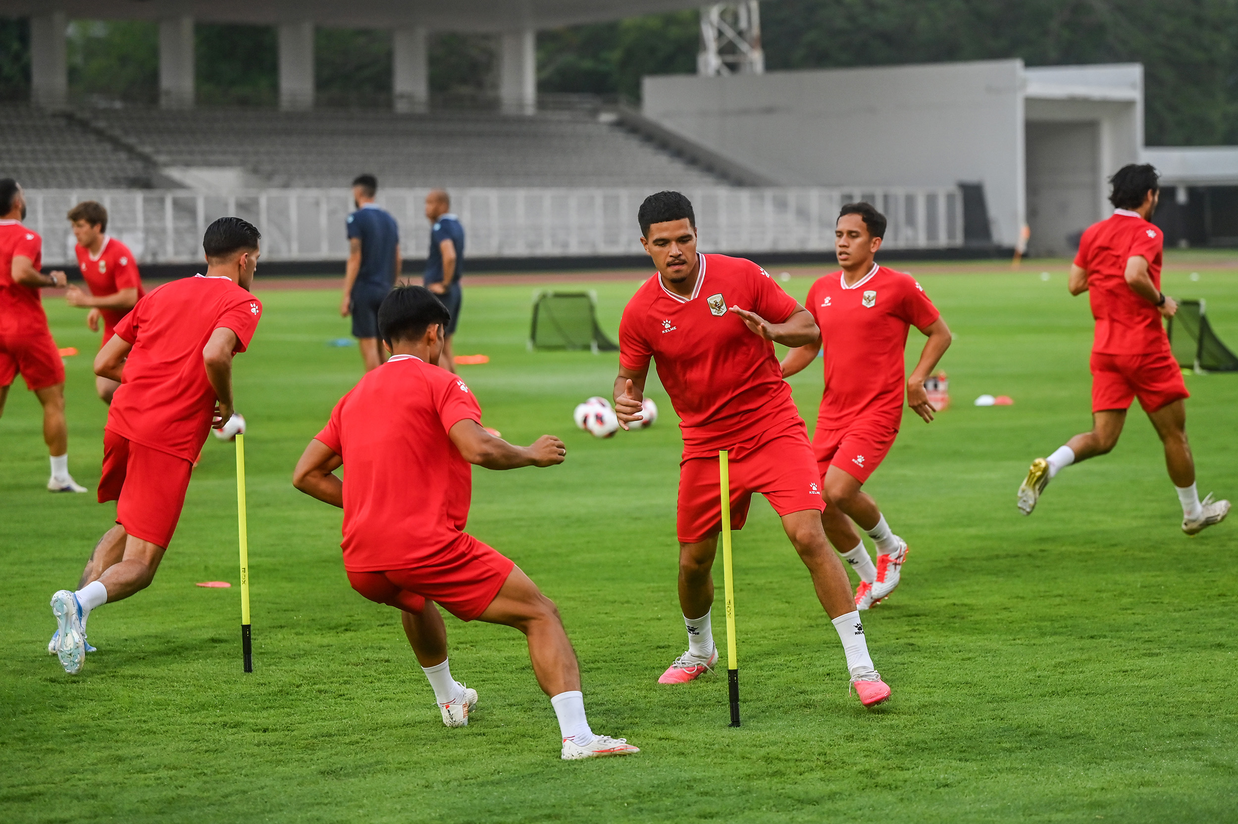 Skuad pemain menjalani sesi latihan Timnas Indonesia dengan seragam latihan merah di lapangan hijau.