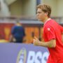 Pemain baru Timnas Indonesia berambut pirang mengenakan jersey latihan merah sedang berlari di lapangan.