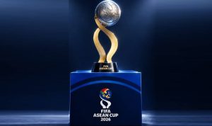 Trofi kejuaraan sepak bola FIFA ASEAN Cup 2026 dengan bola emas dan desain elegan di atas podium biru.