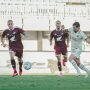 Pemain PSM Makassar berjersey merah marun menguasai bola di bawah tekanan pemain Arema FC.